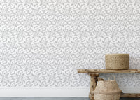 Grey damask wallpaper behind wooden bench and woven baskets.