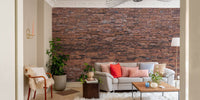 Industrial style brick wall mural behind a grey couch and wooden coffee table.