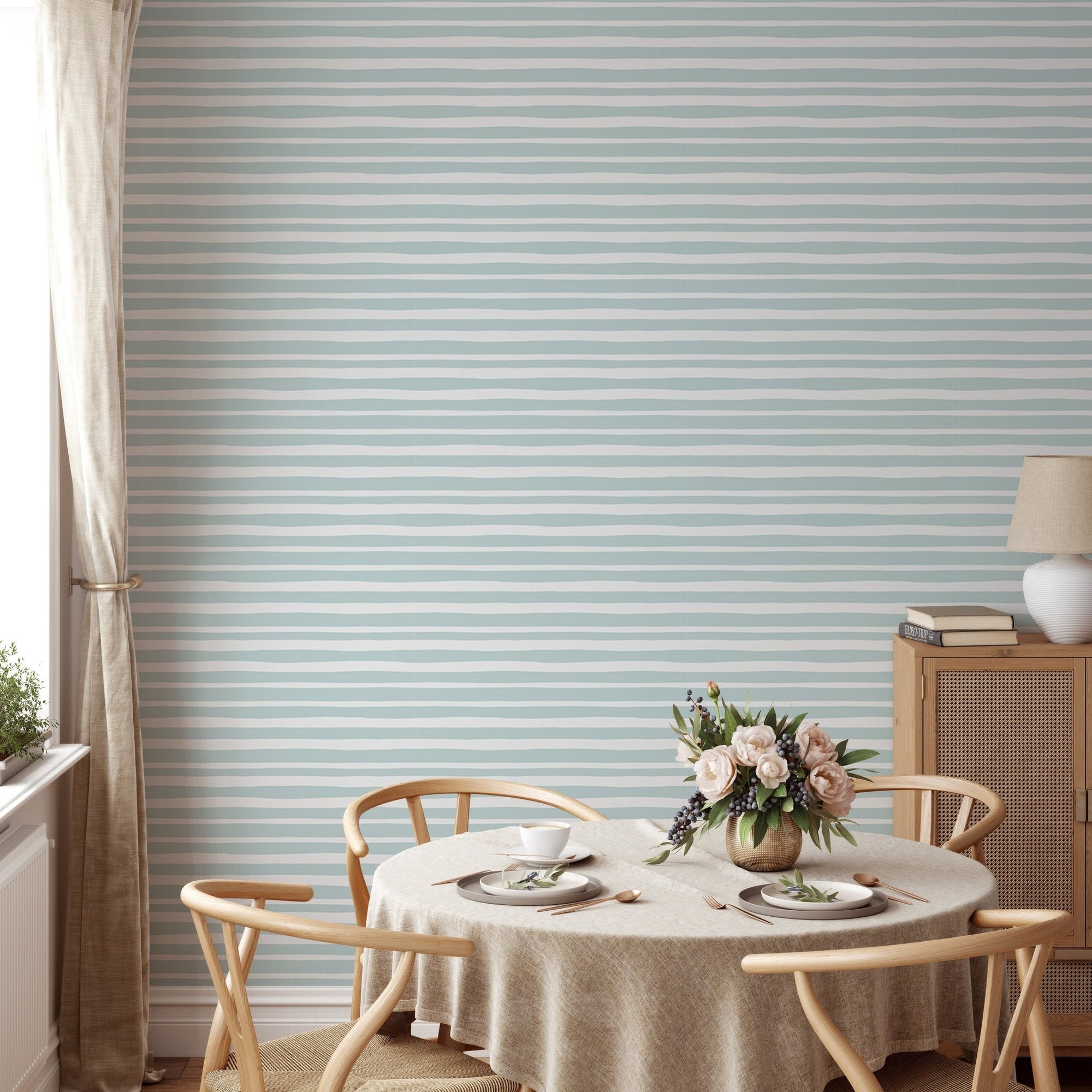 Sea green horizontal striped wallpaper in a dining room with wooden chairs.