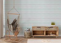 Living space featuring a wooden rocking chair against sea green striped wallpaper.