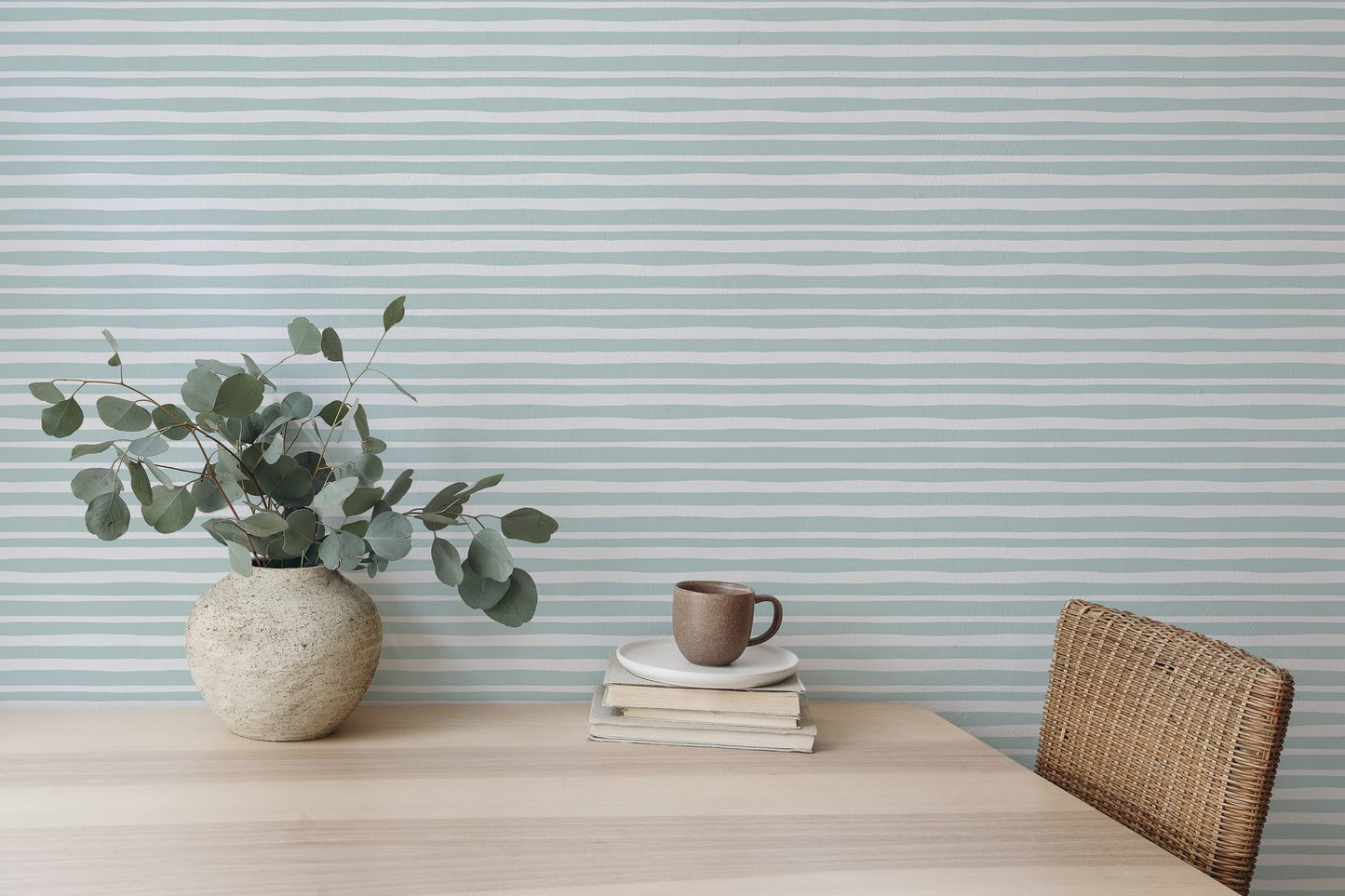 Dining room desk setup with sea green horizontal striped wallpaper and green plants.