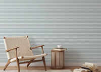 Modern living area with a wooden chair and sea green striped wallpaper.