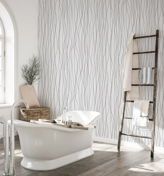 Bright bathroom with a bathtub and textured wavy wallpaper.