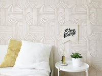 Bedroom wallpaper with cream swell lines behind a white bed and side table.