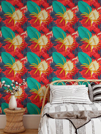 Tropical floral wallpaper with red background behind a wooden bed frame.