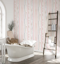 Bathroom featuring pink striped wallpaper behind a white bathtub and wooden ladder.