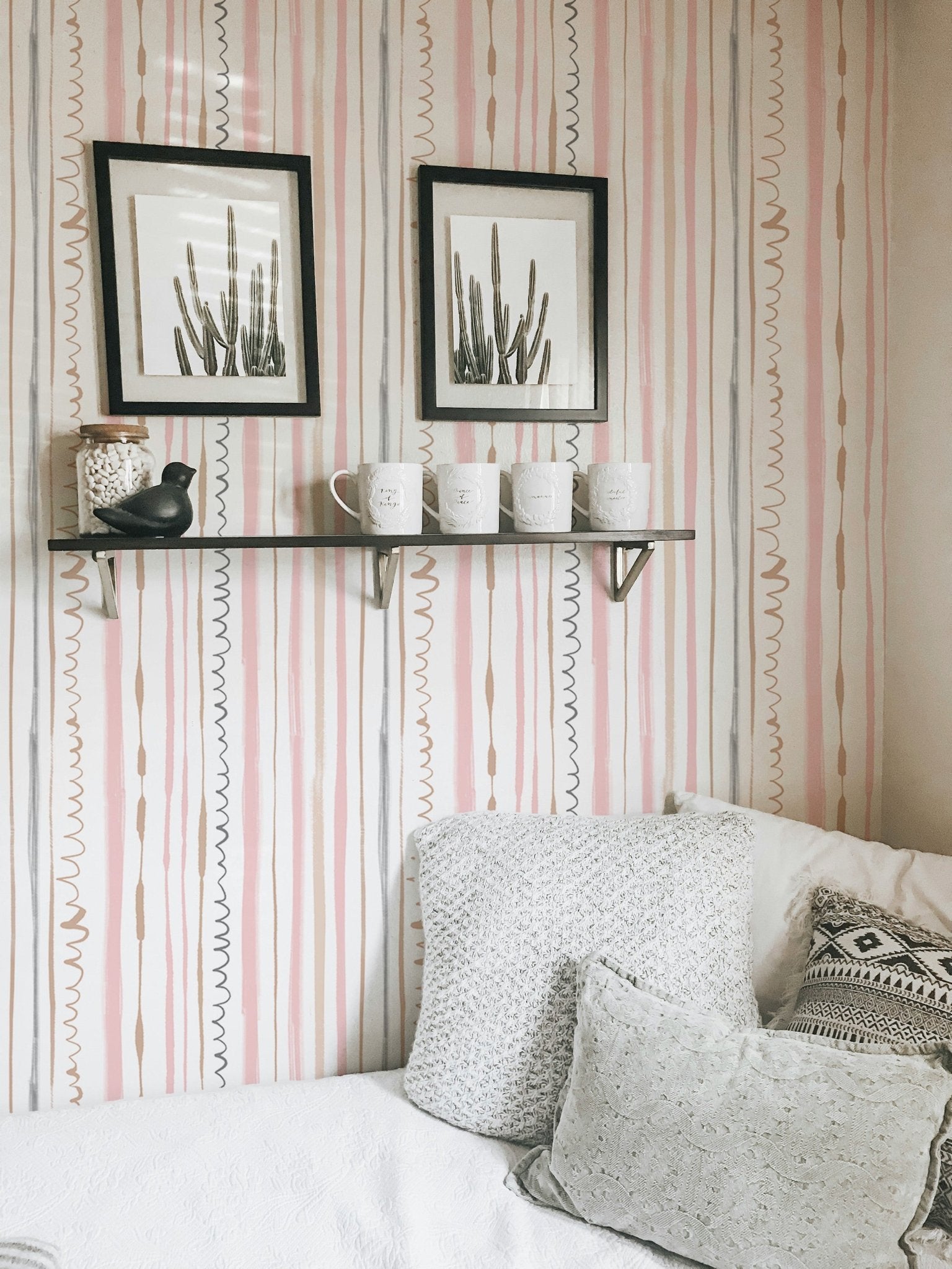 White sofa in a bedroom with pink vertical pattern wallpaper.