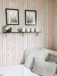 White sofa in a bedroom with pink vertical pattern wallpaper.