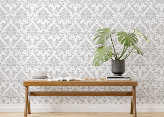 Damask wallpaper with gray pattern behind a wooden bench and green plant.