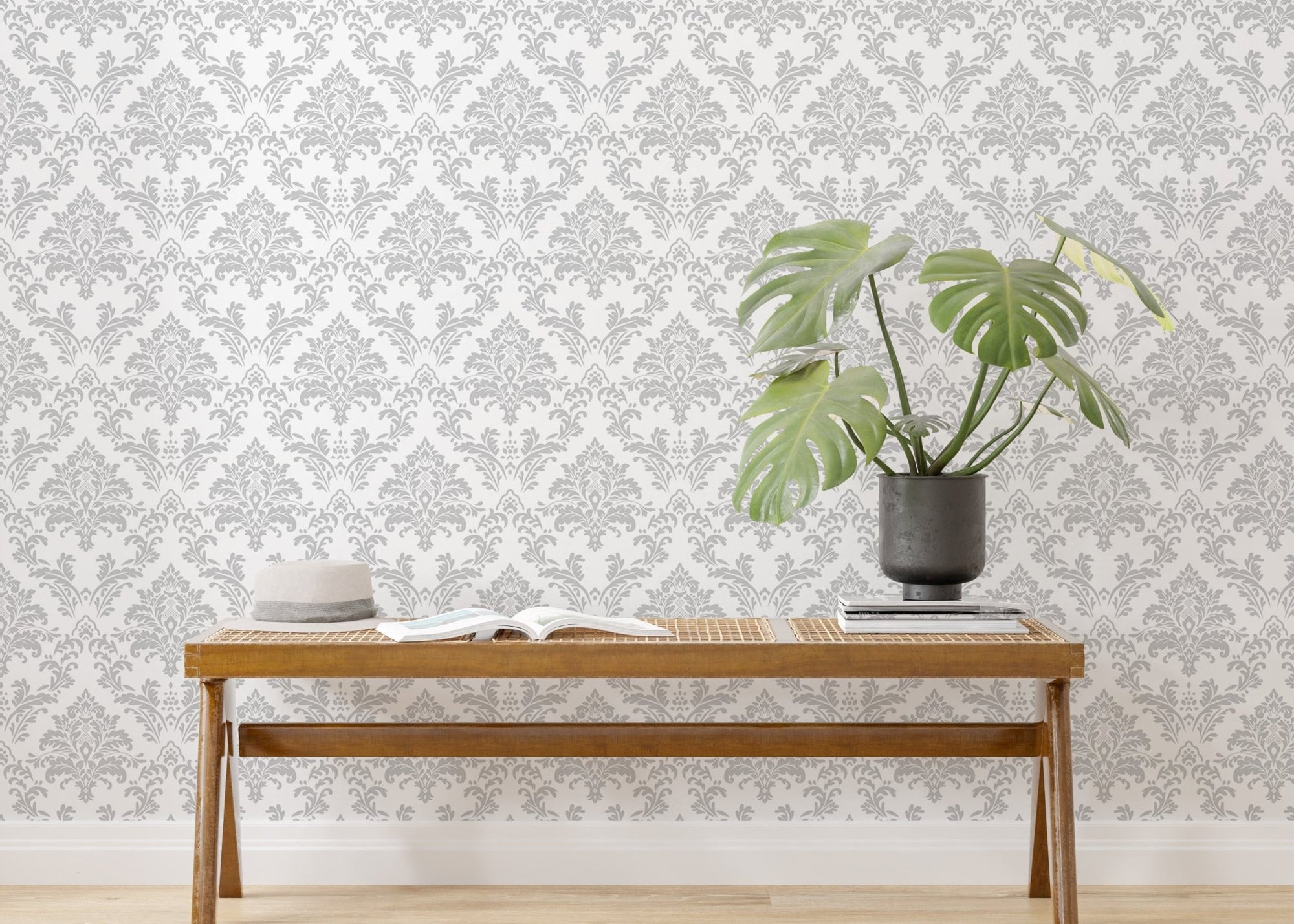 Damask wallpaper with gray pattern behind a wooden bench and green plant.