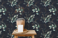 Botanical floral wallpaper behind a wooden shelf with a ceramic vase and white sofa.