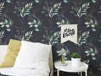 Dark floral wallpaper on a bedroom wall featuring a white framed picture and yellow pillow.