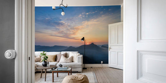 Serene sunset over mountains wallpaper with orange horizon and misty hills.