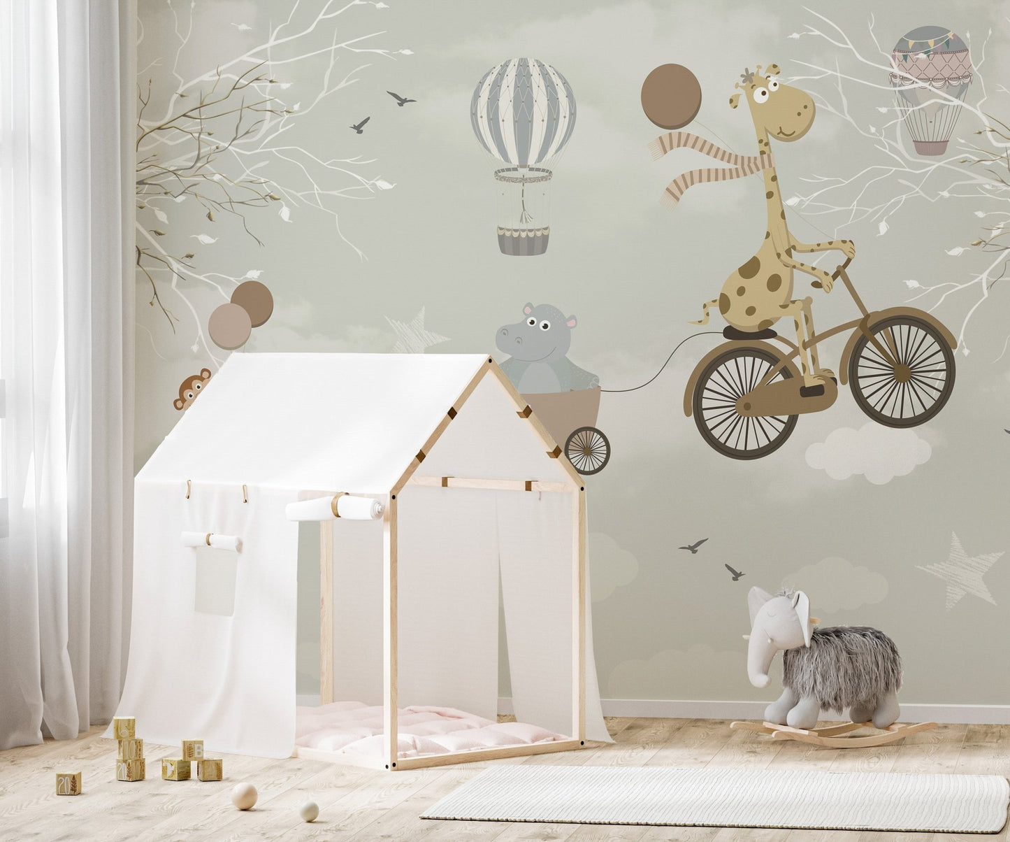 Giraffe on a bicycle wallpaper mural behind a play tent in a neutral nursery.