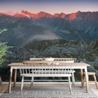 Mountain range wall mural in a dining area with wooden table and bench.