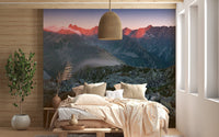 Sunset mountain mural behind a wooden bed frame and pendant light