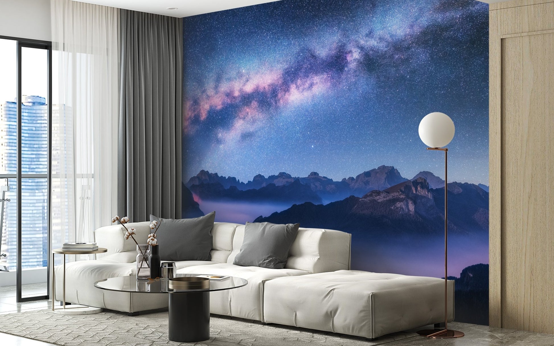 Alpine peaks landscape mural behind a white couch in a minimalist apartment.