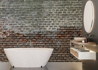 Bathroom interior with aged brick wall mural behind a white freestanding tub.