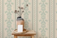 Vertical damask striped wallpaper behind a ceramic vase on a wooden stool.