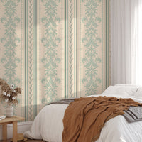 Damask pattern wallpaper in a bedroom with a brown throw and wooden bedside table.
