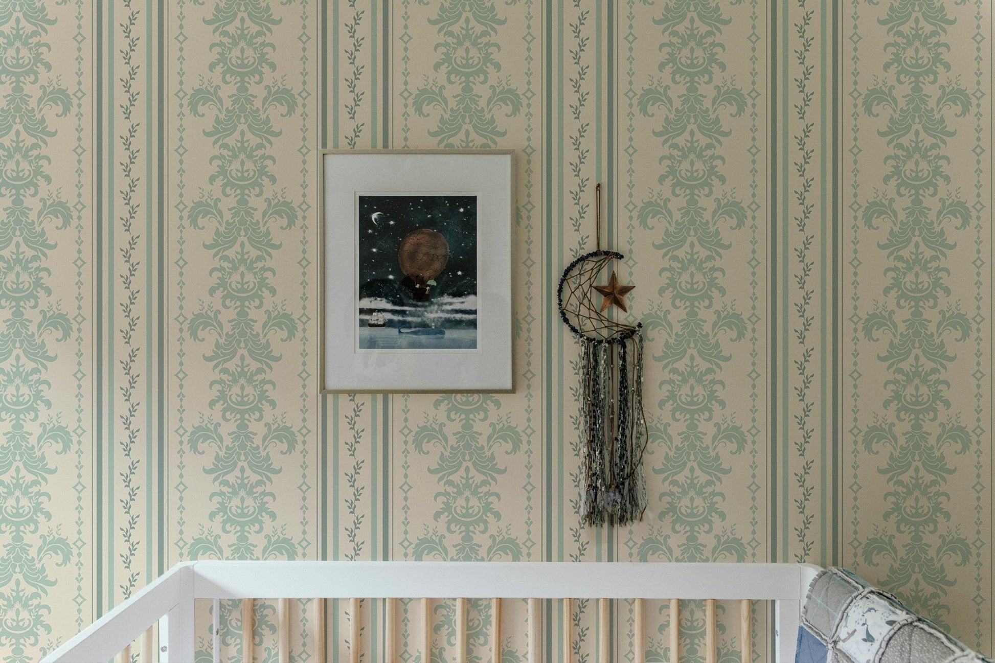 Vintage damask wallpaper with a framed picture above a white baby cot.
