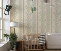 Beige and green damask wallpaper in a nursery with a wooden crib and white curtains.