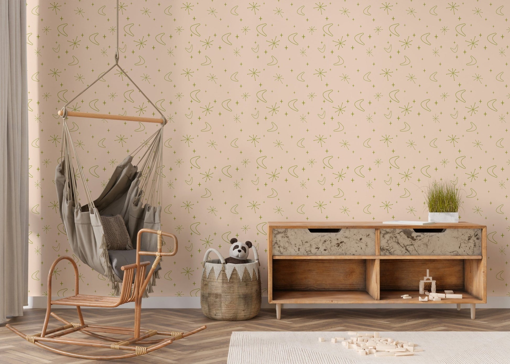 Moon and star pattern wall mural in a nursery area with a hanging swing chair.
