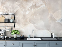 Stone texture wall mural behind a kitchen sink and black cabinetry.