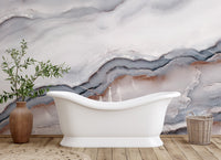Marble effect wall mural behind a white porcelain tub and terracotta vase.