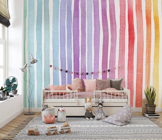 Artistic rainbow wallpaper behind a daybed with grey and pink cushions.