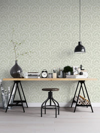 Sage green damask wallpaper in home office with black desk and industrial stool