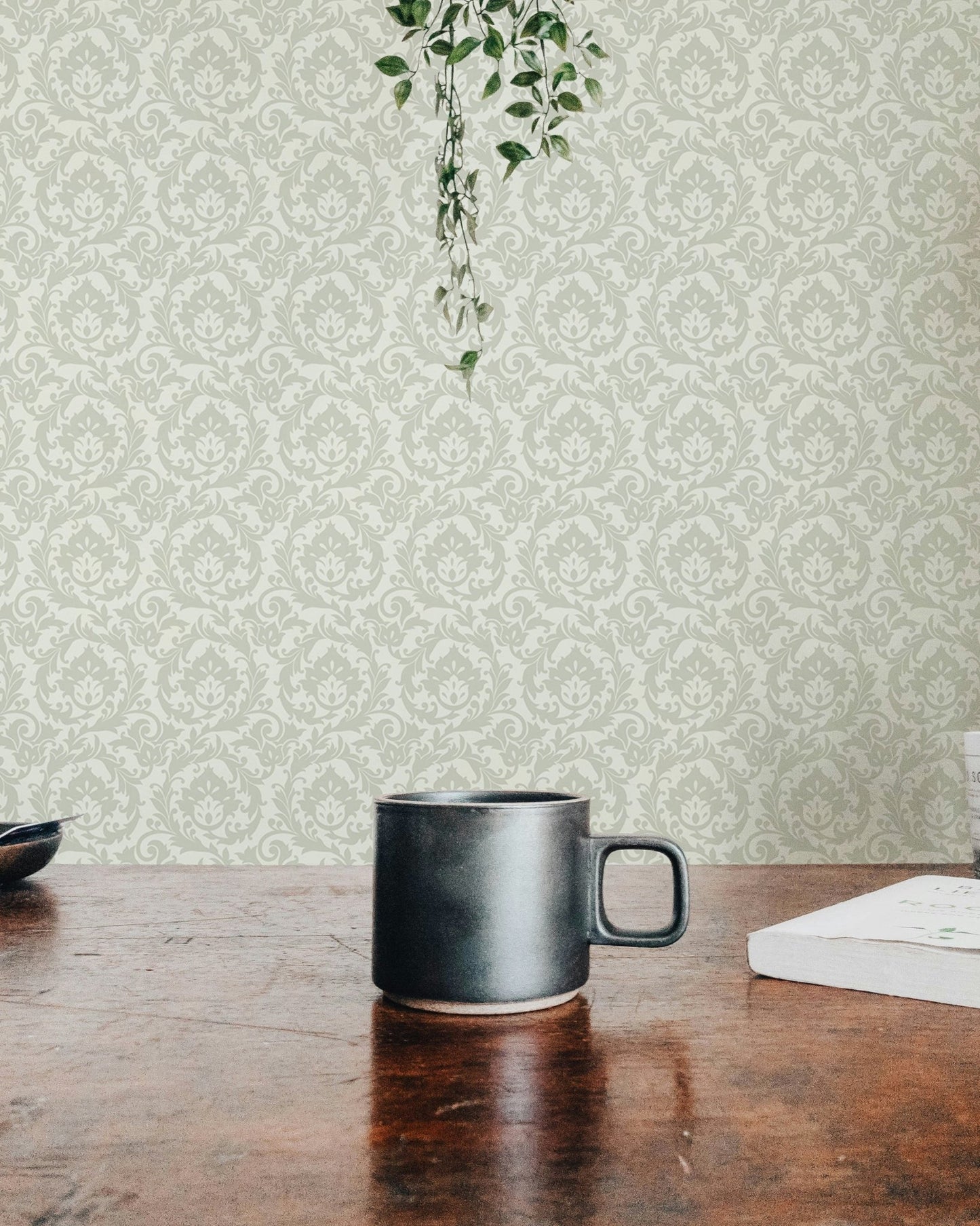 Sage green damask wallpaper backdrop for dark mug on a wooden tabletop