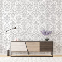 Stylish Rococo White Damask Peel and Stick Wallpaper behind a modern sideboard and lamp.