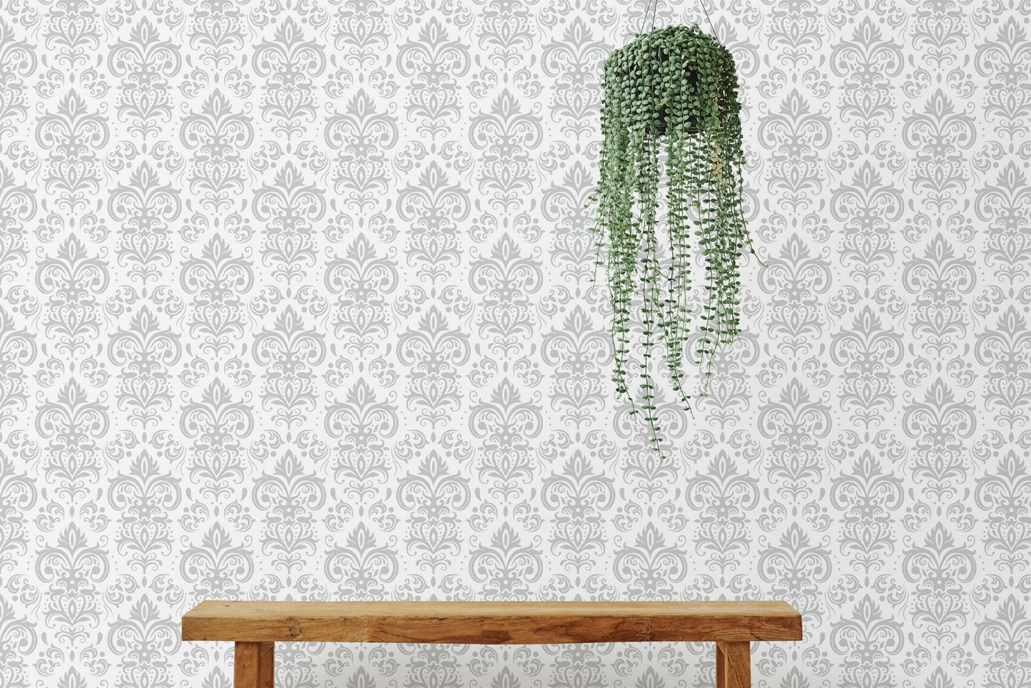 Minimalist wooden bench against a white damask wallpaper with hanging greenery.