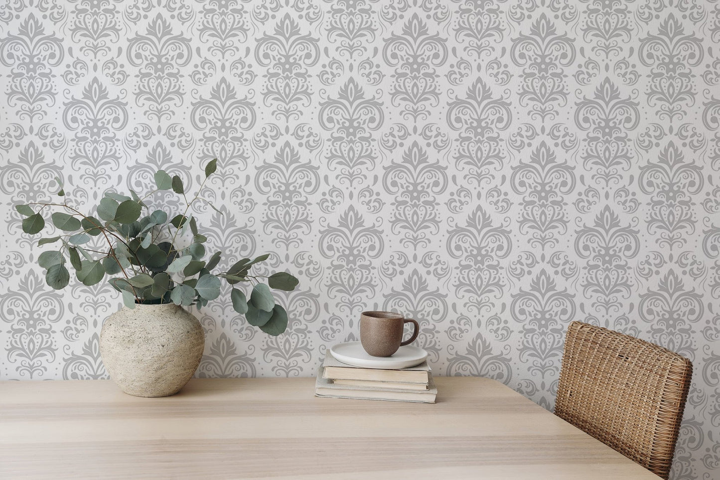 Stylish Rococo White Damask Peel and Stick Wallpaper behind a dining table and plant.