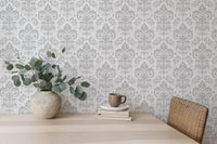 Stylish Rococo White Damask Peel and Stick Wallpaper behind a dining table and plant.