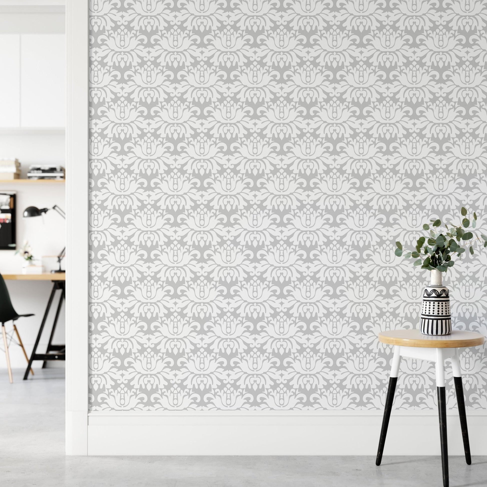 Grey and white damask wallpaper in a bright hallway with a tripod stool.