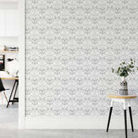 Grey and white damask wallpaper in a bright hallway with a tripod stool.