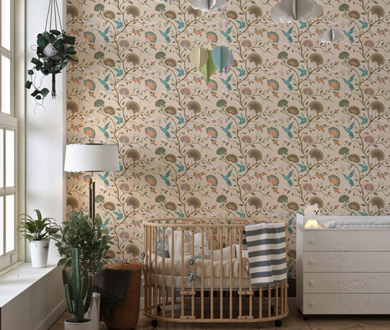 Stylized flowers and humming birds blossom garden wallpaper in a nursery with a crib.
