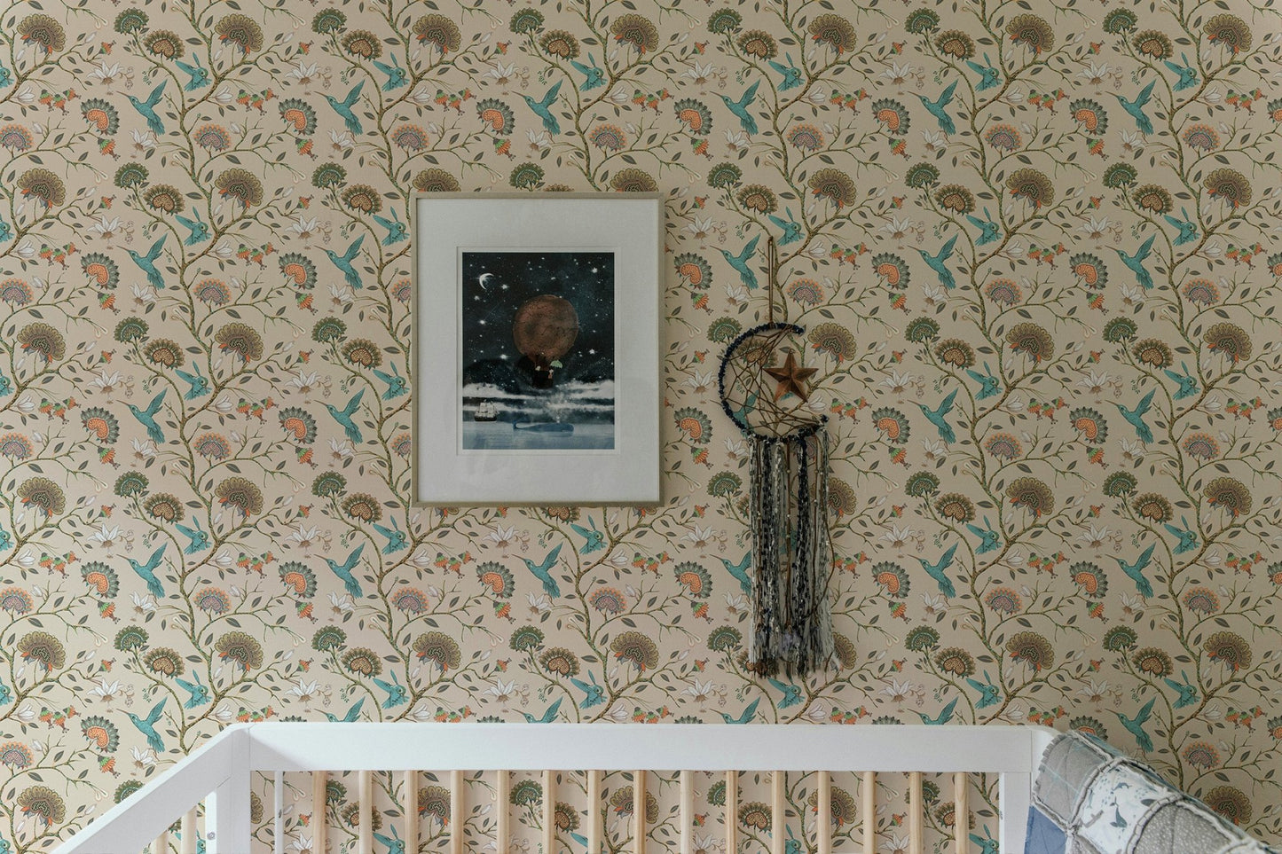 Flower wallpaper in a child's room with a white crib and picture frame.