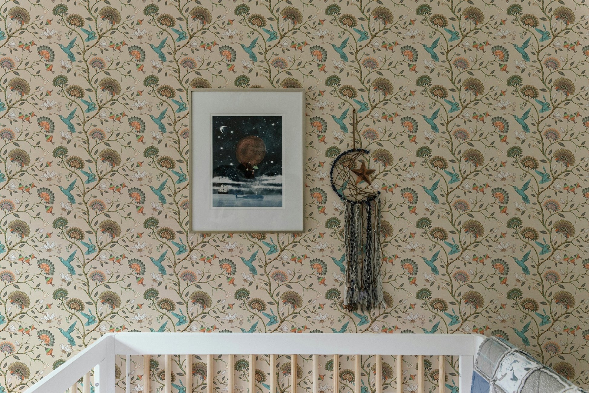 Flower wallpaper in a child's room with a white crib and picture frame.
