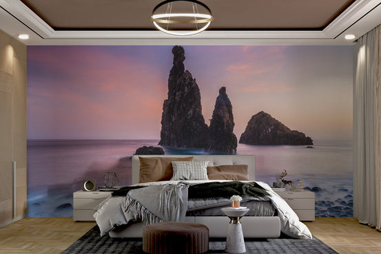 Sunset coastal rock wallpaper with dark sea stacks and purple sky.