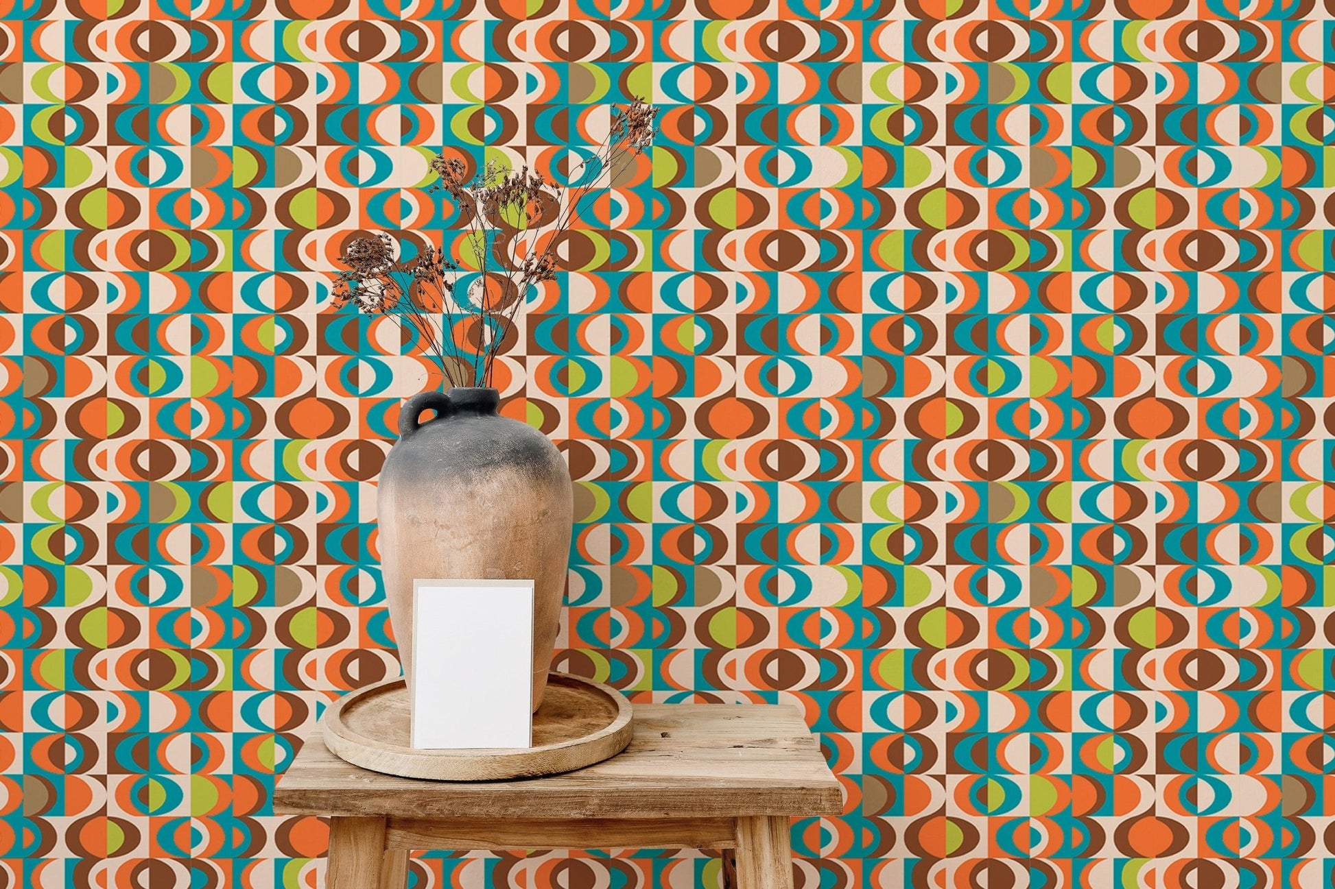 Colorful repeat pattern wall mural behind a small wooden table and ceramic vase.