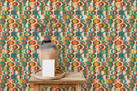 Colorful repeat pattern wall mural behind a small wooden table and ceramic vase.