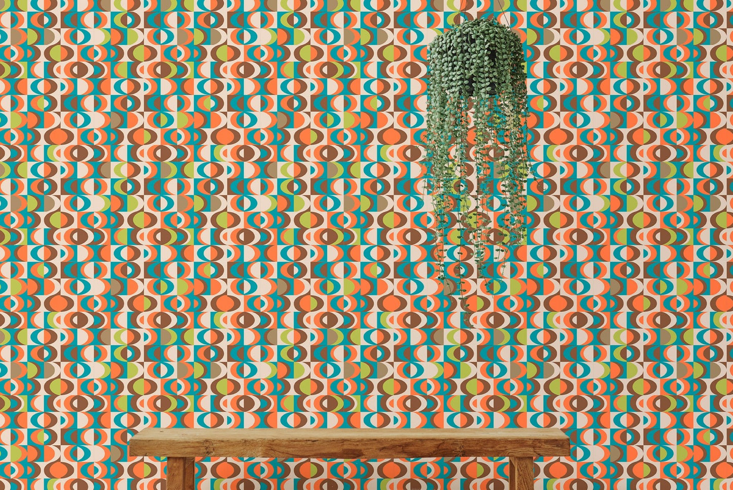 Orange and teal repeat pattern wall mural behind a wooden bench and hanging plant.