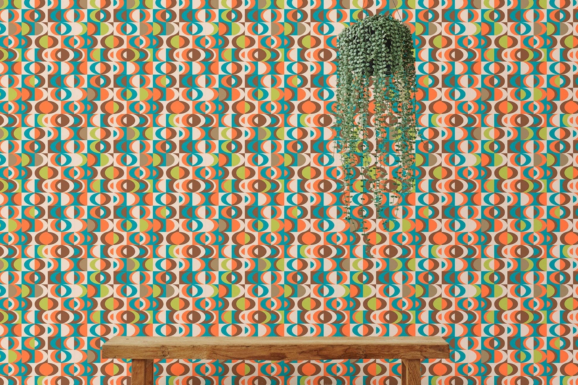 Orange and teal repeat pattern wall mural behind a wooden bench and hanging plant.