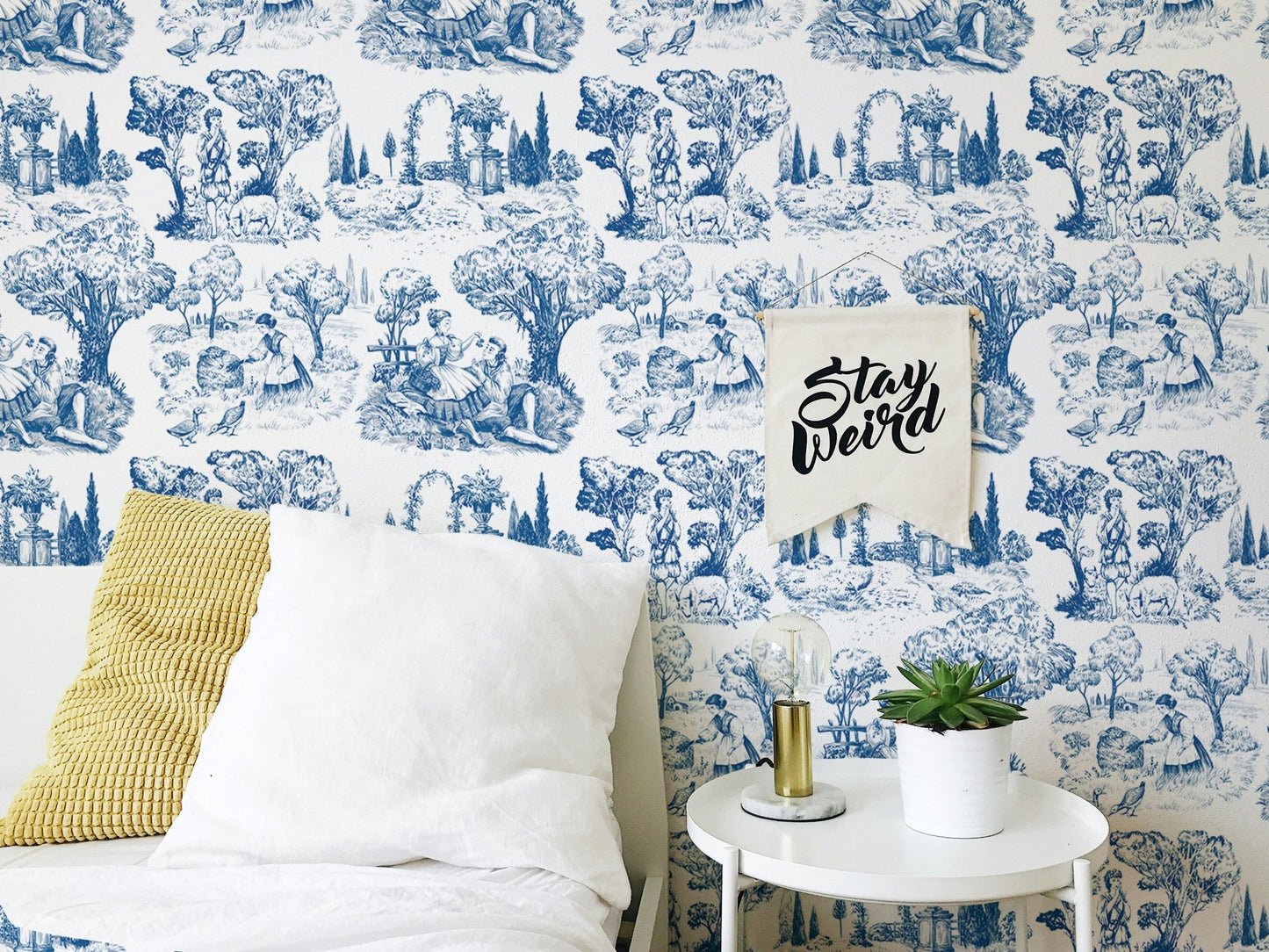 French style wallpaper in a bedroom with white pillows and a yellow cushion.