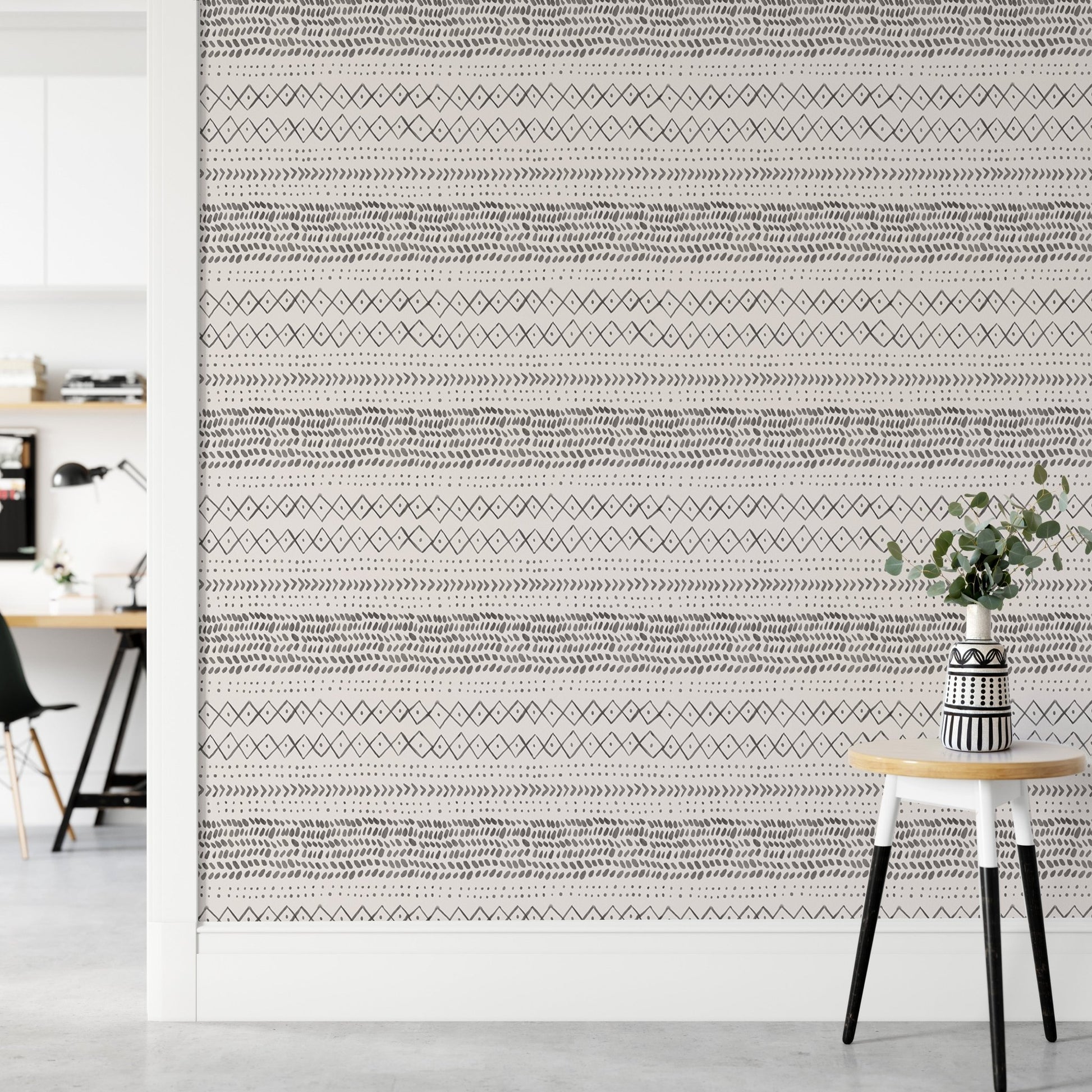 Minimalist hallway with a small stool and ethnic watercolor wall mural.