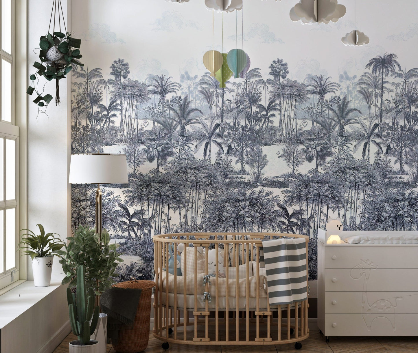 Tropical Forest Blue Wall mural in a nursery with a wooden crib and lamp.