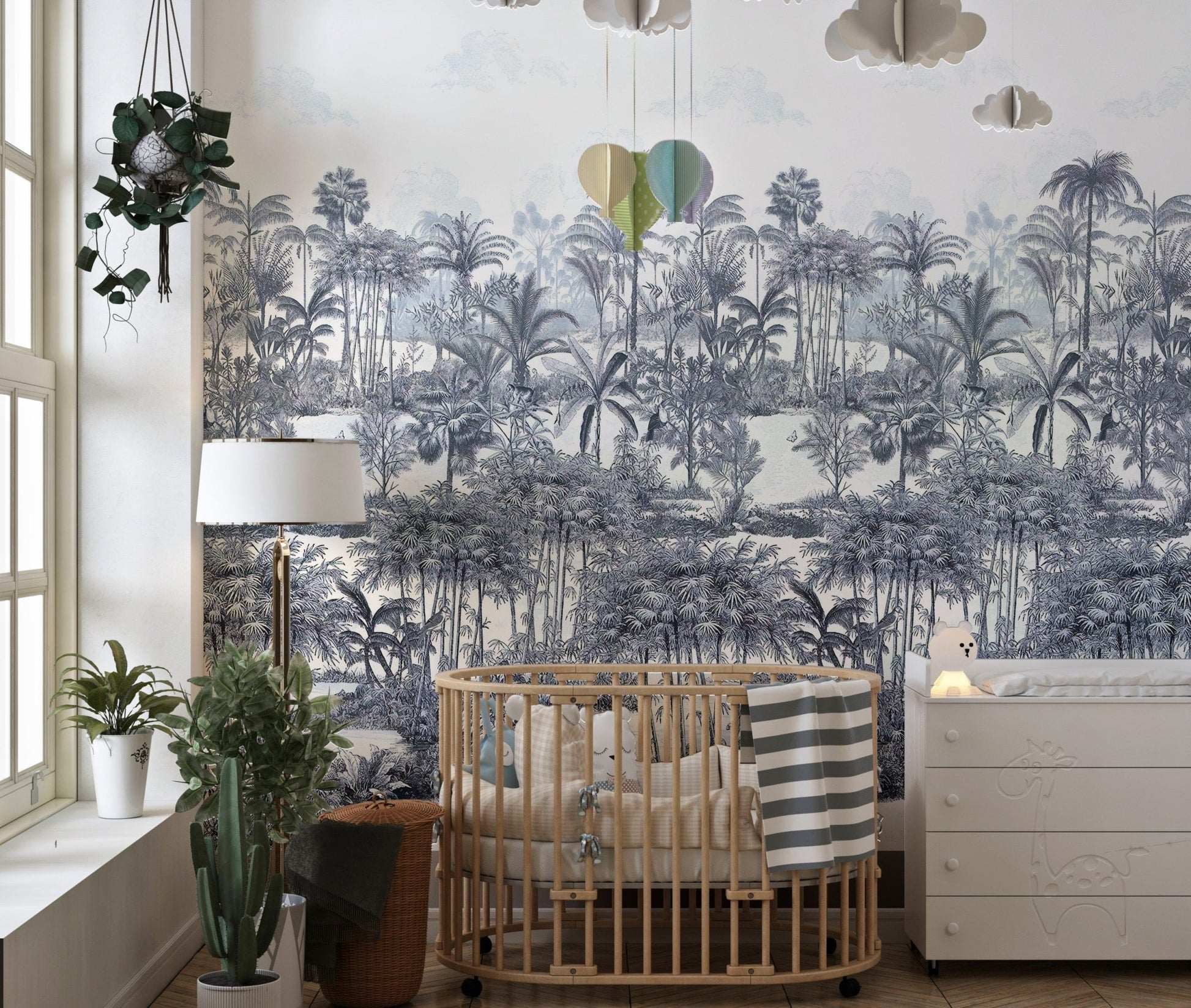 Tropical Forest Blue Wall mural in a nursery with a wooden crib and lamp.
